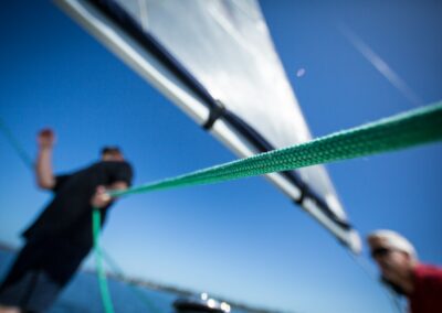person holding green rope near boat sail